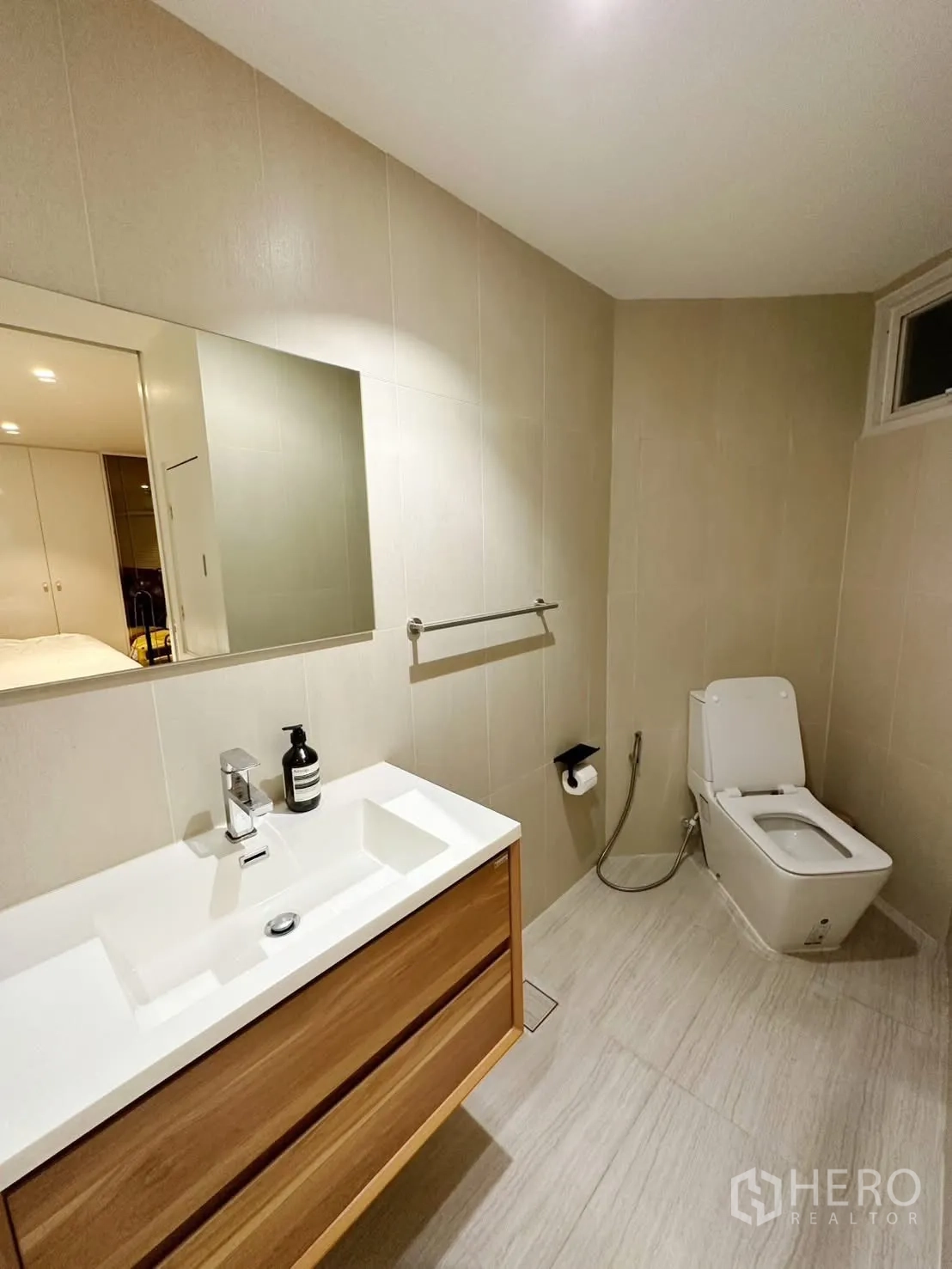 Condominium for rent or sale in Watthana, Bangkok - Bright bathroom with vanity, mirror, and toilet.