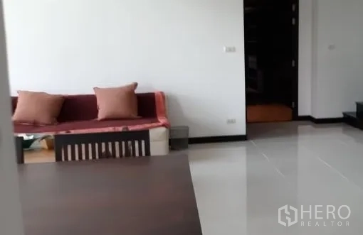 Condominium for rent in Watthana, Bangkok - Another angle of the open-plan lounge and dining area with glossy tile floors and a cozy sofa.