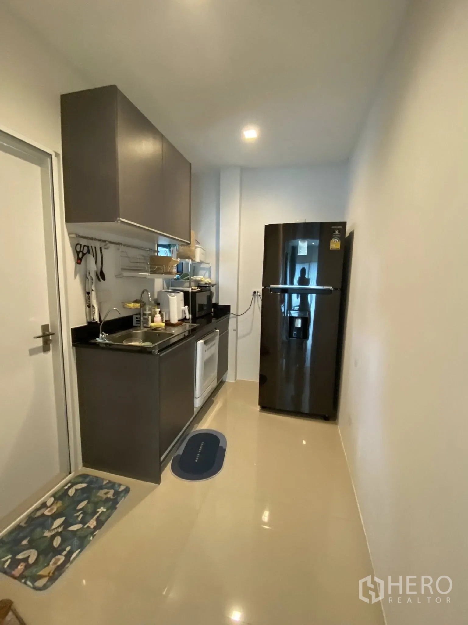 Detached House for sale in Saphan Sung, Bangkok - Compact galley kitchen with upper cabinets, sink, and refrigerator.