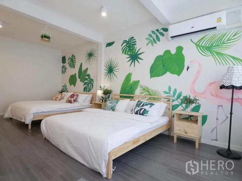 Townhouse for rent in Khlong Toei, Bangkok - Bedroom view showing twin double beds, leafy mural with a pink flamingo and a wall-mounted air conditioner.