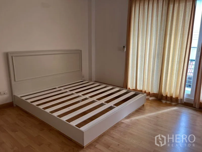 ทาวน์เฮาส์ ให้เช่าในWang Thonglang, Bangkok - ห้องนอนมีโครงเตียงสีขาว พื้นไม้ และทางออกสู่ระเบียง