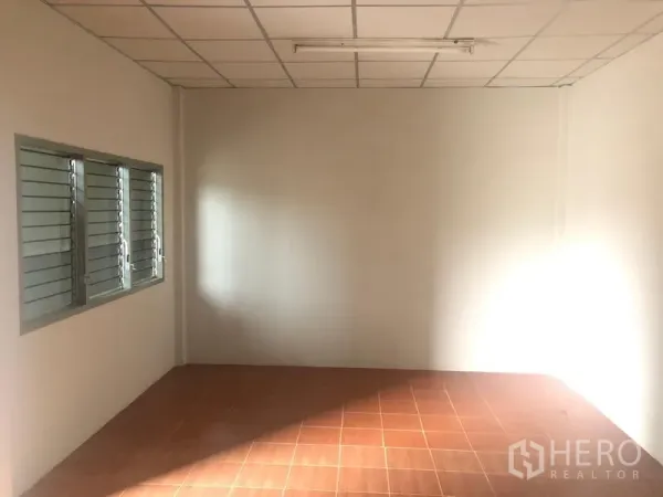 货栈 出租在Pathum Thani - 仓库内办公室，瓷砖地面、白墙和百叶窗。