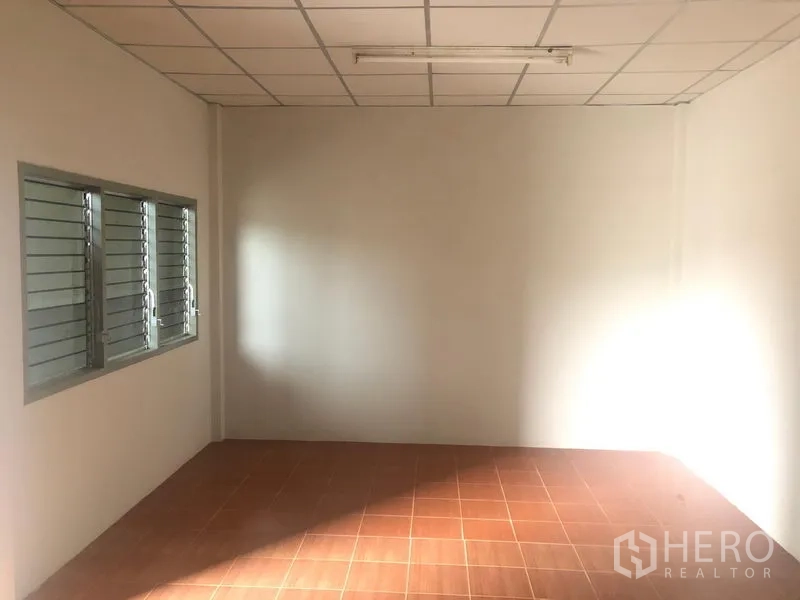 货栈 出租在Pathum Thani - 仓库内办公室，瓷砖地面、白墙和百叶窗。