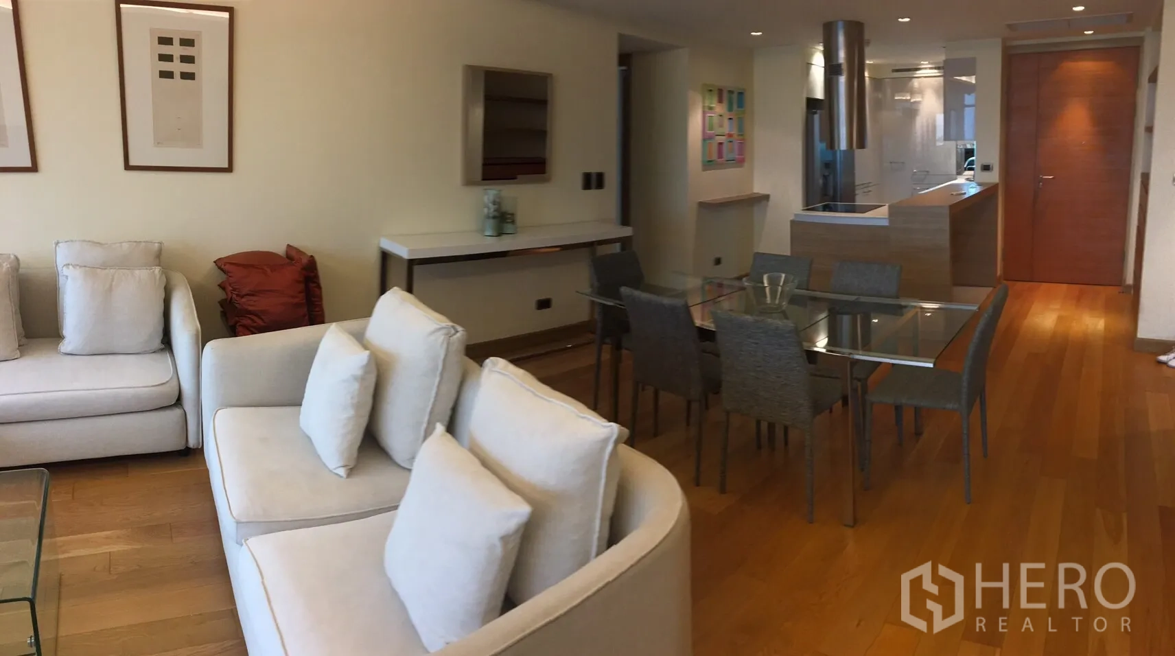 คอนโด ให้เช่าในPhaya Thai, Bangkok - ห้องนั่งเล่นและรับประทานอาหารแบบโอเพ่นแพลน โซฟาสีครีม โต๊ะกระจก พื้นไม้ และครัวสมัยใหม่