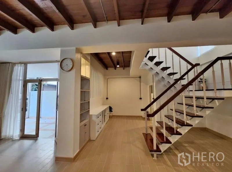 Townhouse for sale - Open-plan hallway with wooden staircase, exposed ceiling and built-in storage.