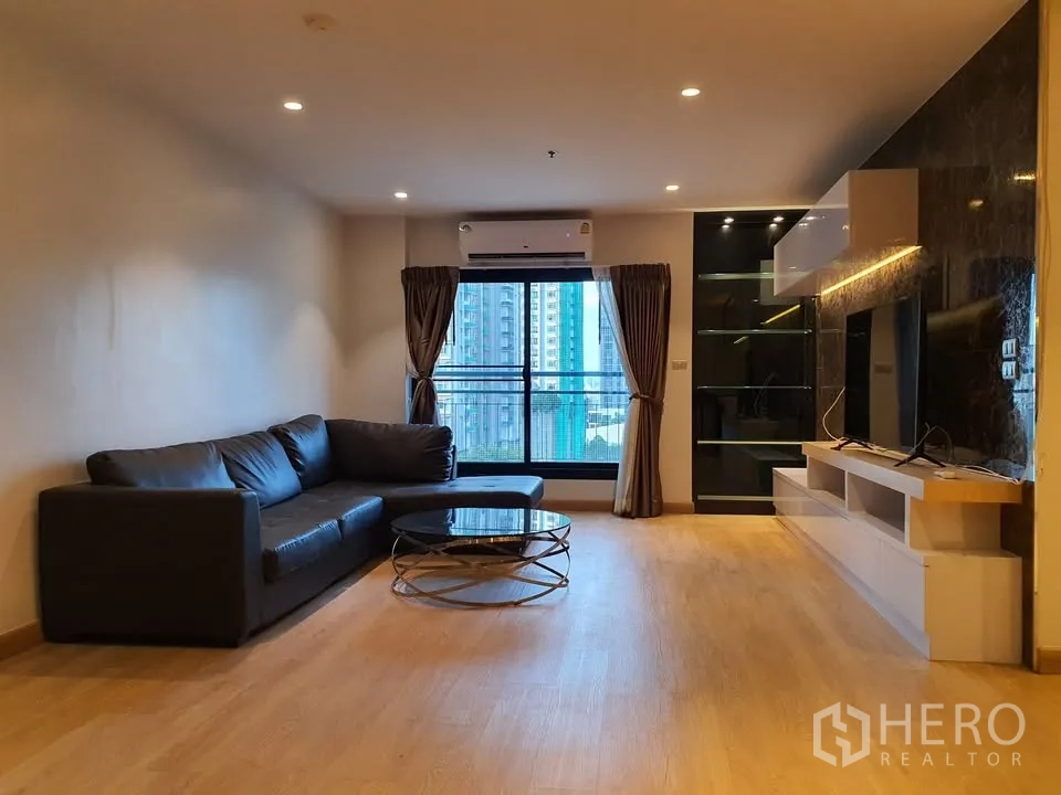 公寓 for rent in Watthana, Bangkok - 客厅L形皮沙发、圆形玻璃茶几与阳台城市景观