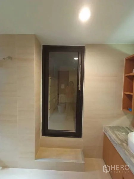Home Office for rent in Watthana, Bangkok - Bathroom corner with tall window, shelving and light tiles.