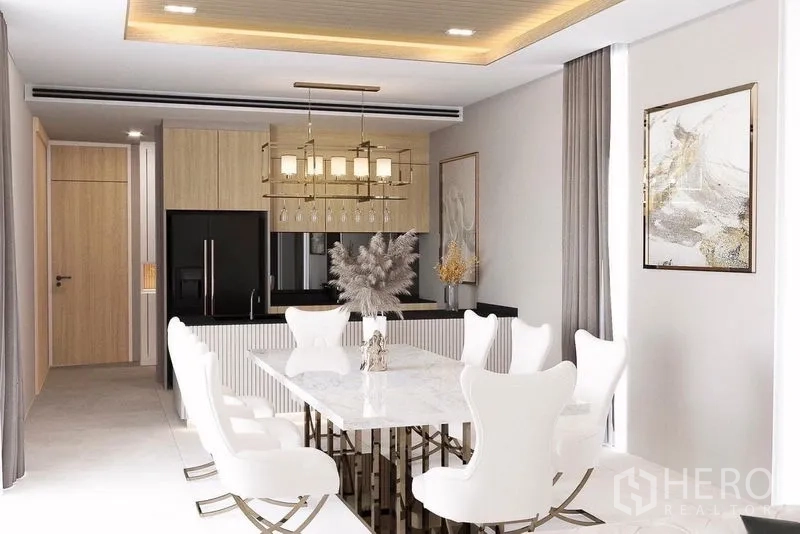 Detached House for sale in Suan Luang, Bangkok - Formal dining room with marble-top table, designer chandelier and view to a compact kitchen.