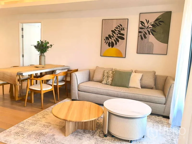 อพาร์ทเมนท์ ให้เช่า - ห้องนั่งเล่นและรับประทานอาหารสว่างไสว พร้อมโซฟาและกรอบภาพตกแต่งผนัง