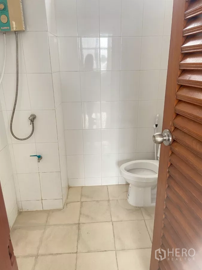 Shophouse for rent in Prawet, Bangkok - Tiled bathroom with toilet, handheld bidet and shower unit.