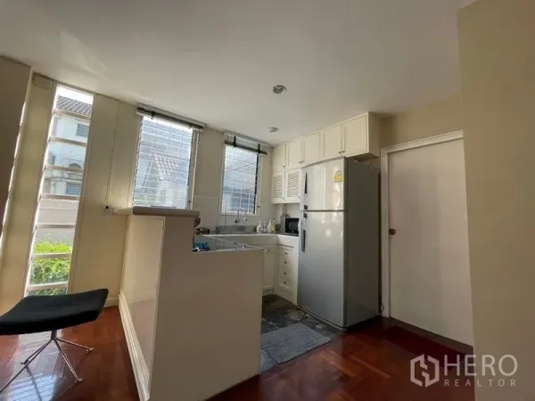 Detached House for rent in Khlong Toei, Bangkok - Bright Western kitchen with white cabinetry, large windows and stainless-steel fridge.