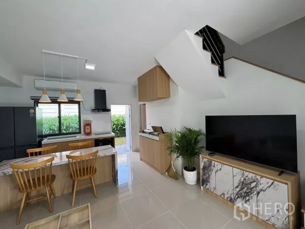 ทาวน์เฮาส์ ให้เช่าในBang Phli, Samut Prakan - ห้องนั่งเล่นพร้อมทีวีบิลท์อิน บันได และครัวมองออกสู่ลานหลังบ้าน