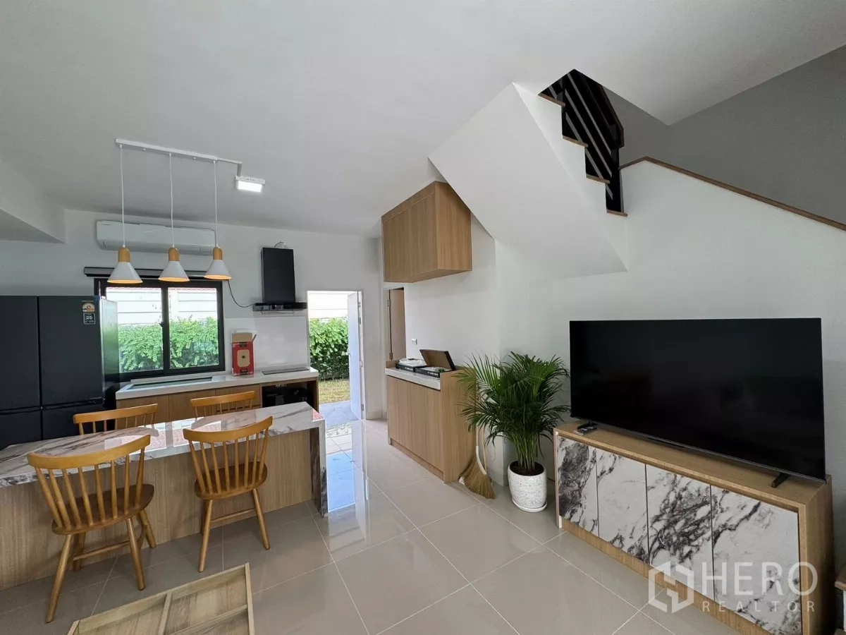 ทาวน์เฮาส์ ให้เช่าในBang Phli, Samut Prakan - ห้องนั่งเล่นพร้อมทีวีบิลท์อิน บันได และครัวมองออกสู่ลานหลังบ้าน