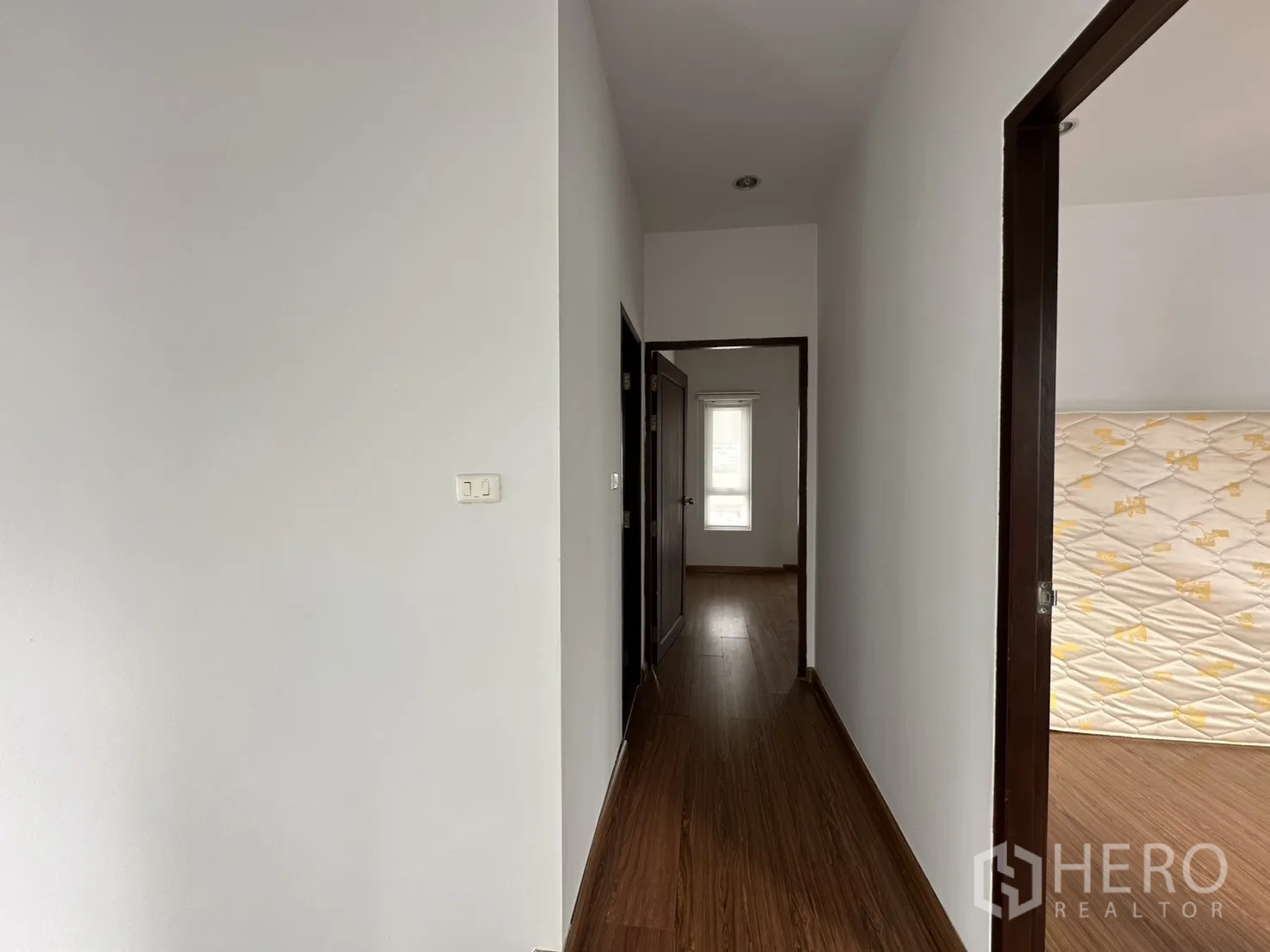 Home Office for rent in Watthana, Bangkok - Upstairs hallway with wood flooring and white walls leading to bedrooms.