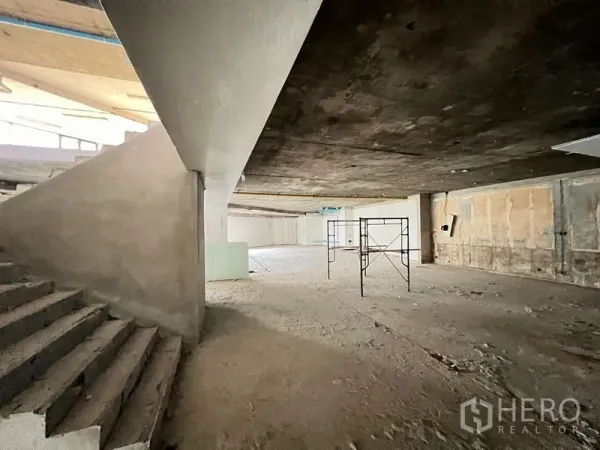 零售空间 出租在Watthana, Bangkok - 宽敞未装修内部，设有室内楼梯与脚手架，适合展厅布局。