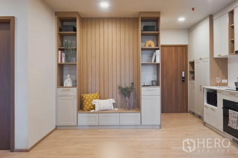 Condominium for sale in Suan Luang, Bangkok - Living area feature wall with wood paneling, built-in shelving and bench seat.