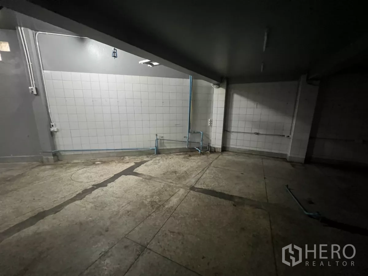 อาคารพาณิชย์ ให้เช่าในWatthana, Bangkok - พื้นที่หลังร้านปูกระเบื้องแสงสว่างน้อย มีโคมไฟยาวและร่องระบายน้ำ.