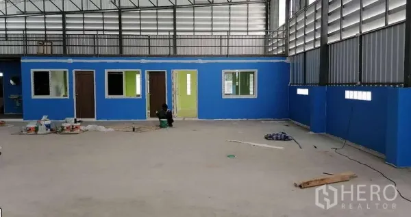 Warehouse for rent in Mueang Samut Sakhon, Samut Sakhon - Built-in office block under mezzanine with multiple doors and windows facing the warehouse floor.