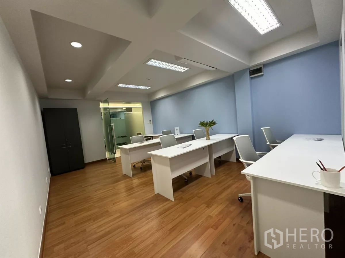Office Space for rent in Watthana, Bangkok - Open workspace with multiple desks and chairs facing a glass-partitioned meeting room.