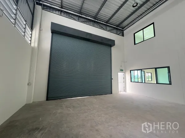 Factory for rent in Bang Phli, Samut Prakan - Loading bay inside the warehouse with oversized roller door, high ceiling and internal office windows.