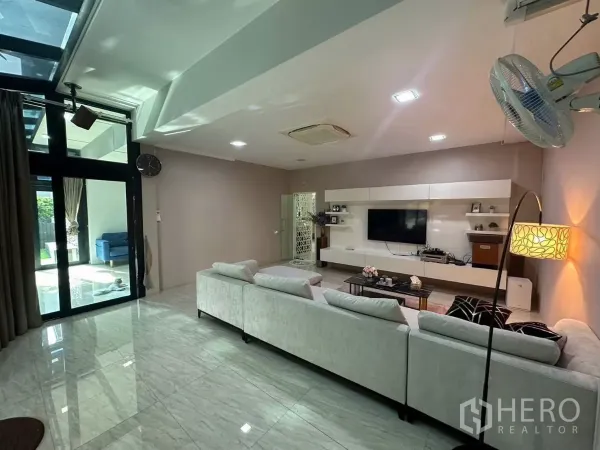 บ้าน ให้เช่าหรือขายในBang Kapi, Bangkok - ห้องพักผ่อนสว่างสดใส ประตูกระจกบานเลื่อนเปิดสู่สวน พร้อมผนังทีวี