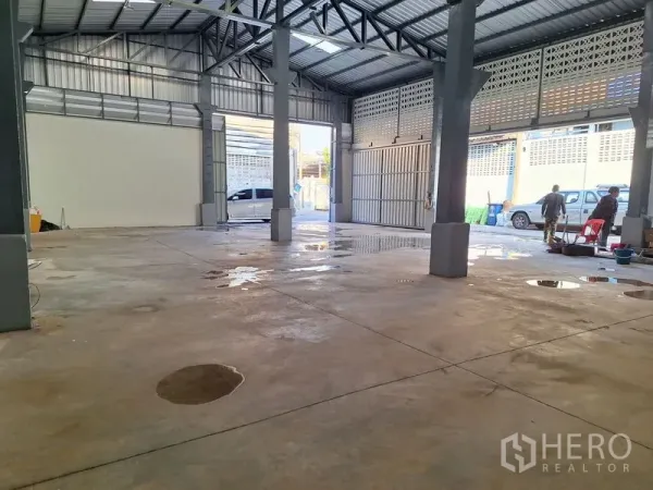 Warehouse for rent in Rat Burana, Bangkok - Open warehouse interior with concrete floor, steel trusses, and a wide vehicle entry bay.