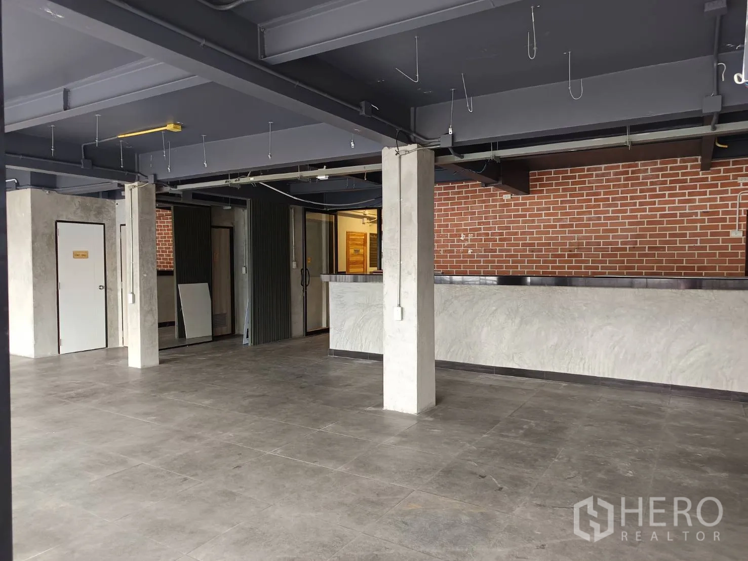 พื้นที่ขายปลีก ให้เช่าในWatthana, Bangkok - พื้นที่ขายพร้อมเคาน์เตอร์บริการ ประตูหลายบาน และผนังอิฐ.