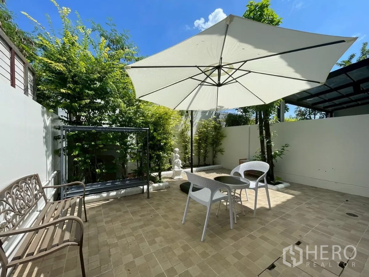 联排别墅 出租在Prawet, Bangkok - 后院露台，遮阳伞、户外椅与防滑地砖。