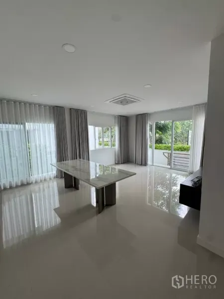 Detached House for rent or sale in Bang Bo, Samut Prakan - Bright open-plan living and dining area with floor-to-ceiling windows and marble table.