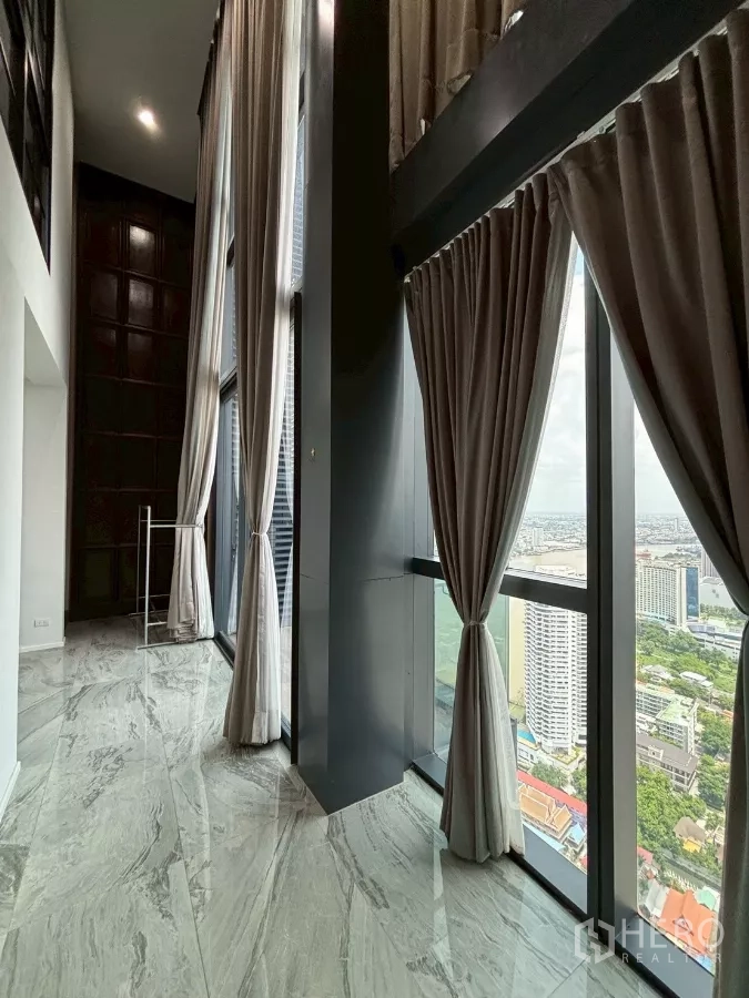 Condominium for sale in Bang Kho Laem, Bangkok - Double-height corridor lined with floor-to-ceiling windows and long curtains offering panoramic city views.
