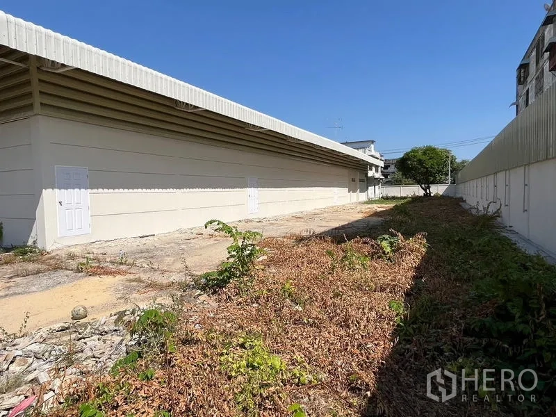 Warehouse for rent or sale - Side walkway and service doors along the warehouse next to the perimeter fence.