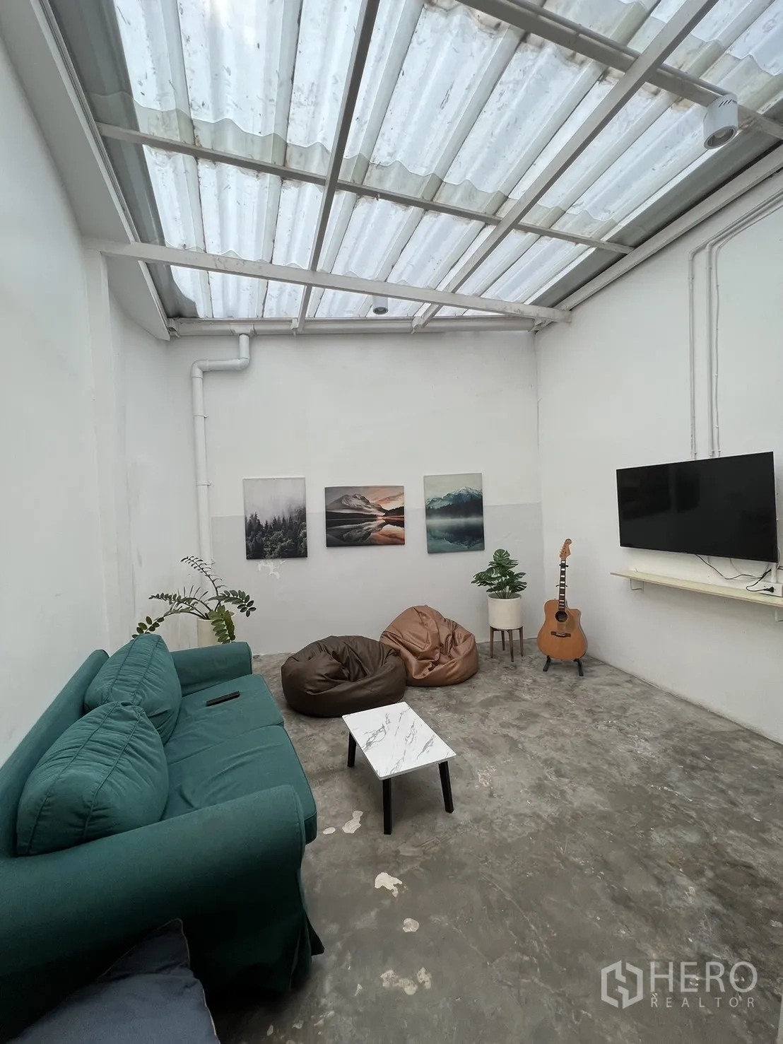 อาคารพาณิชย์ ให้เช่าในKhlong Toei, Bangkok - เลานจ์รับแสงธรรมชาติด้วยหลังคาโปร่ง โซฟาสีเขียว ทีวี บีนแบ็ก และกีตาร์