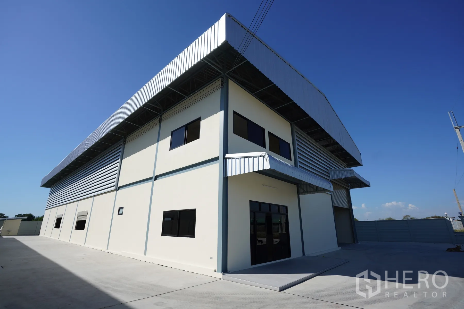 Factory for rent in Mueang Samut Prakan, Samut Prakan - Two-storey office wing attached to the factory with metal cladding and canopies.