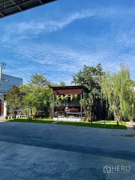 Warehouse for sale in Min Buri, Bangkok - Landscaped garden with a small pavilion and mature trees beside the warehouse yard.
