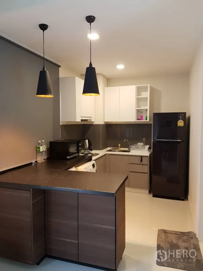 Townhouse for rent or sale in Saphan Sung, Bangkok - Modern kitchen with stone island, pendant lights, built-in cabinets, fridge and washing machine.