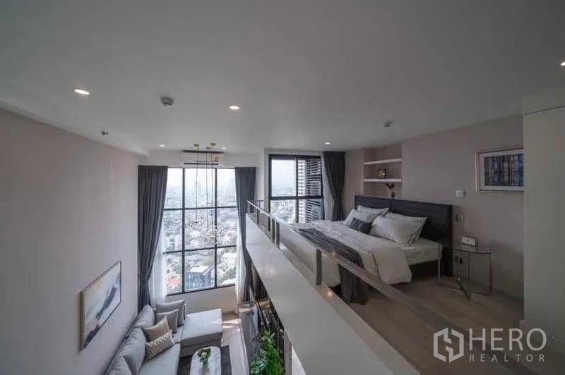 Condominium for rent in Sathon, Bangkok - Mezzanine bedroom with city views through tall windows.