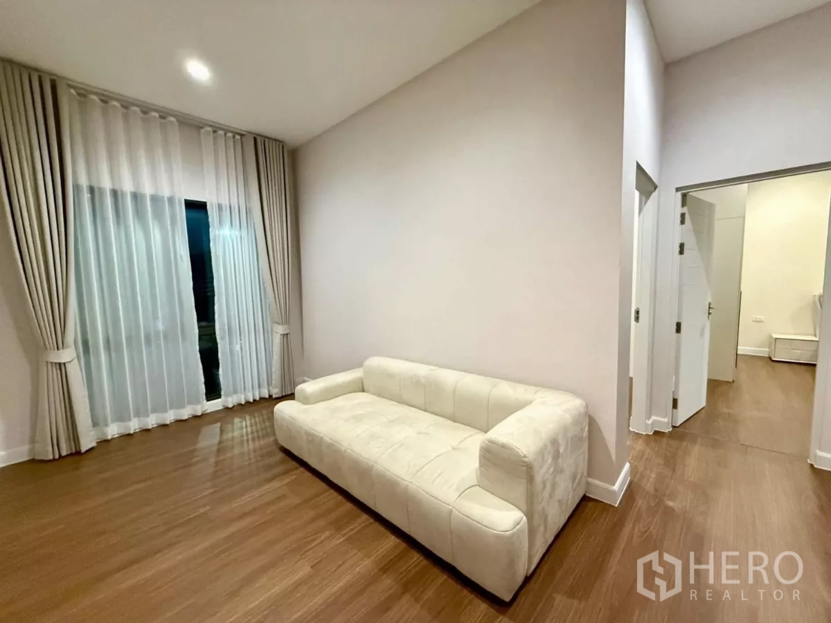 Detached House for rent in Bang Phli, Samut Prakan - Upstairs family lounge with cream sofa, wood floors and sheer curtains.