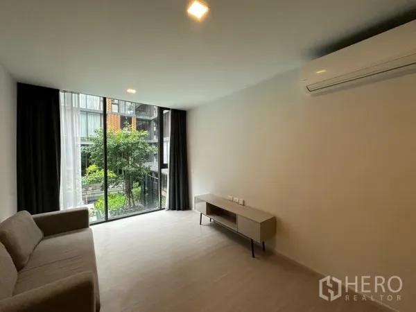 คอนโด ให้เช่าในKhlong Toei, Bangkok - ห้องนั่งเล่นสไตล์มินิมอล มีโซฟา ชั้นวางทีวี แอร์ และประตูกระจกบานเลื่อนมองเห็นสวนและสระ