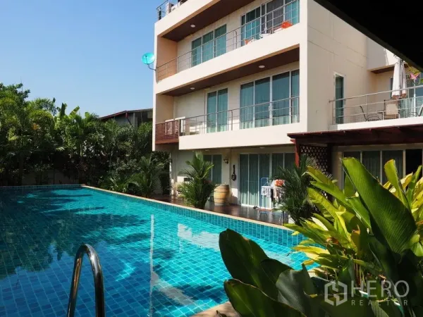 Home Office for sale in Phra Khanong, Bangkok - Three-storey home office with full-length windows overlooking a turquoise private pool and tropical plants.