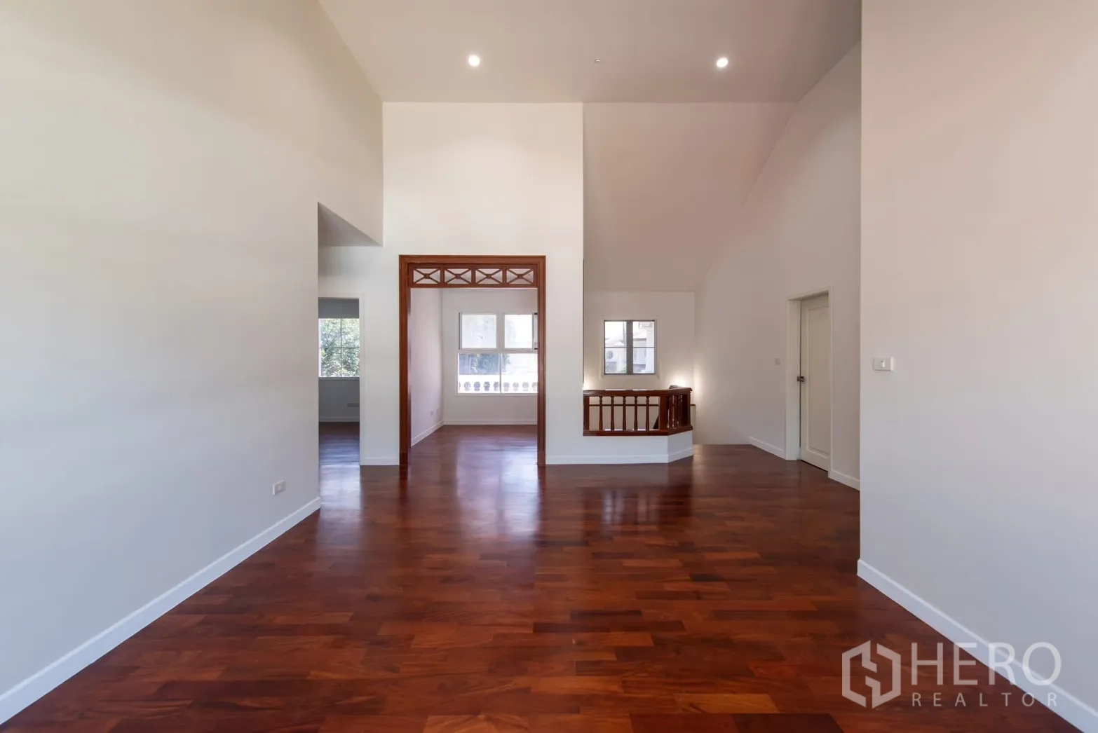 Detached House for sale in Bang Phli, Samut Prakan - Open-plan upstairs hall with wooden flooring, windows and a decorative doorway frame.