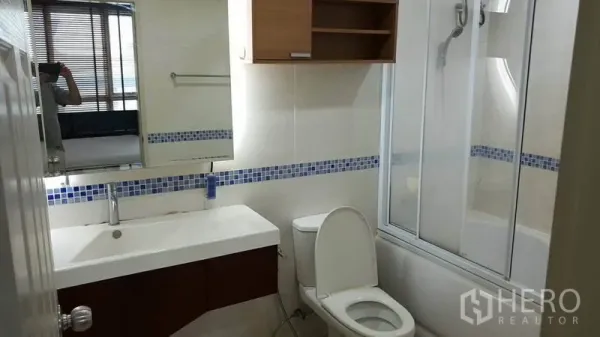 公寓 出租在Bang Rak, Bangkok - 现代浴室，宽台盆、坐便器、带玻璃隔断的浴缸，蓝色马赛克点缀。