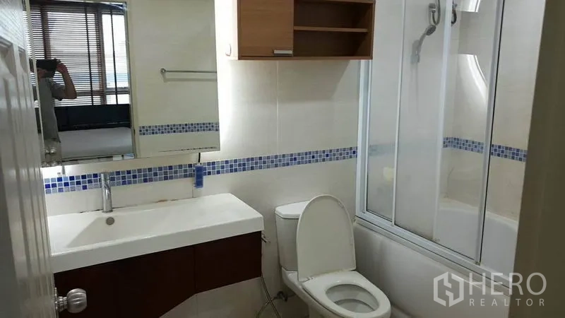 公寓 出租在Bang Rak, Bangkok - 现代浴室，宽台盆、坐便器、带玻璃隔断的浴缸，蓝色马赛克点缀。