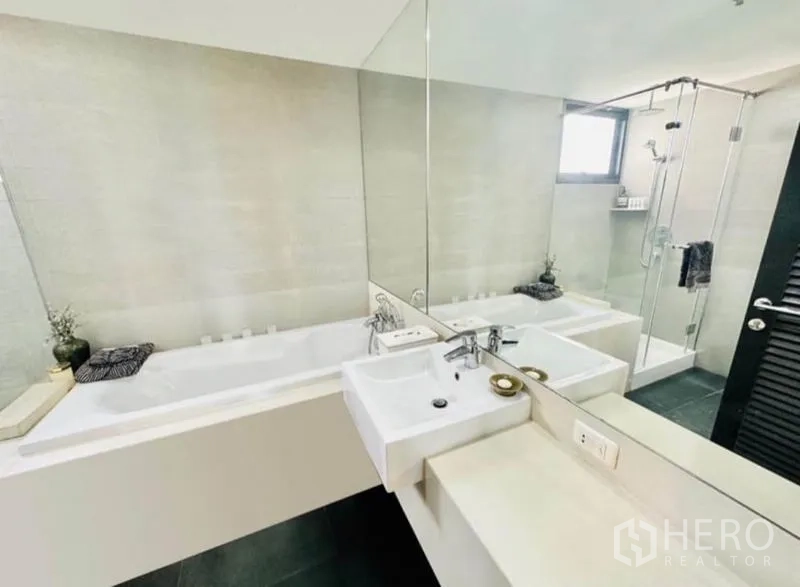 Condominium for rent in Watthana, Bangkok - Modern bathroom with soaking tub, twin basins and a glass‑enclosed shower.