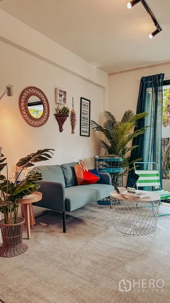 Home Office for rent in Watthana, Bangkok - Living corner with sofa, coffee tables, floor lamp, and large windows facing greenery.