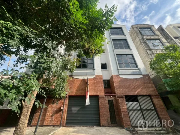 店屋 出租在Phra Khanong, Bangkok - 店屋正立面，宽卷闸门与栅栏入口，上层为白色外墙和大窗。