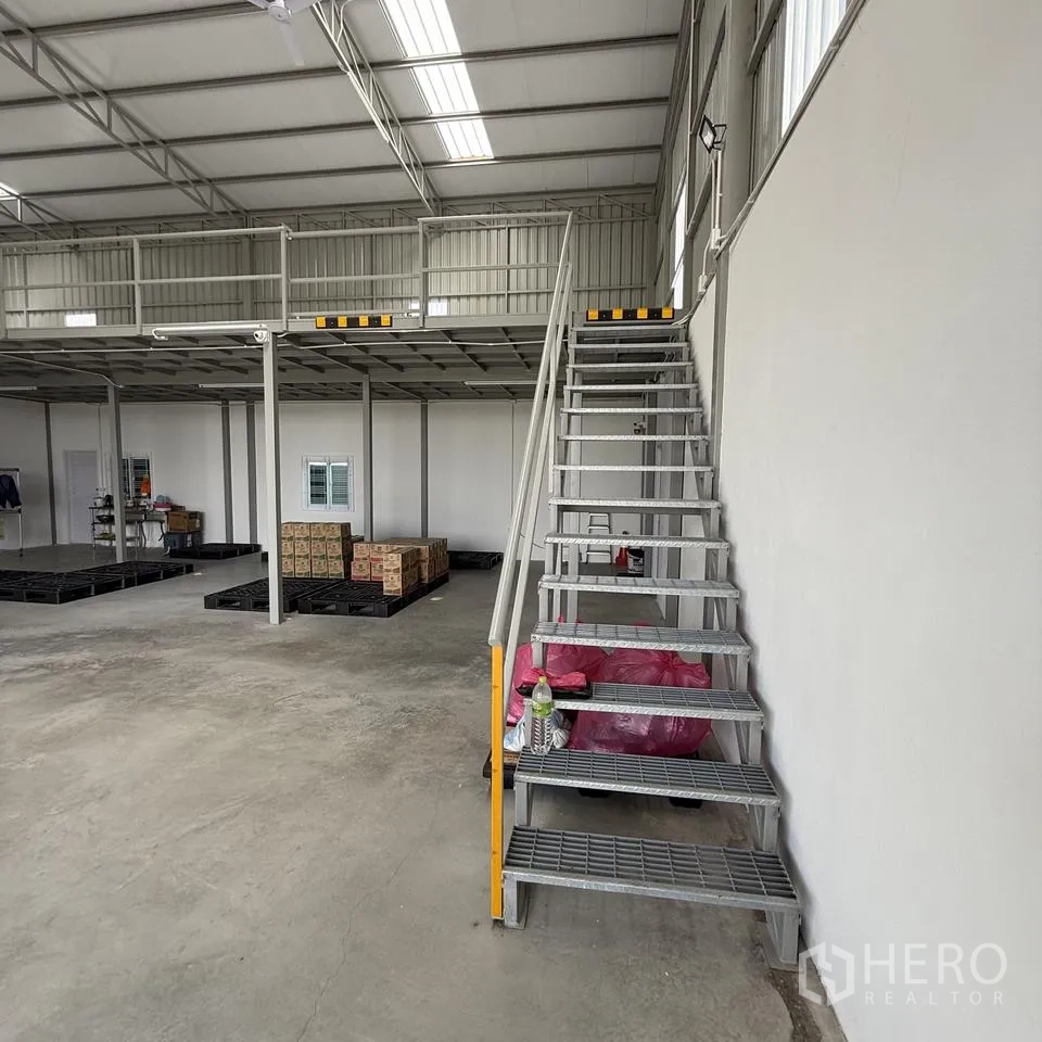 仓库 for rent or sale in Khlong Luang, Pathum Thani - 仓库内设钢梯通往夹层，混凝土地面，摆放有托盘与纸箱。