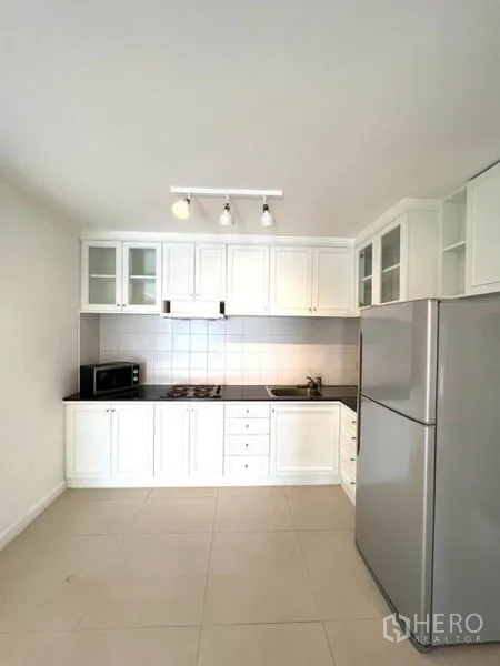 คอนโด ให้เช่าในWatthana, Bangkok - ครัวโทนขาว ตู้กระจกท็อปหินสีดำ เตาไฟฟ้า ไมโครเวฟ และตู้เย็นขนาดใหญ่