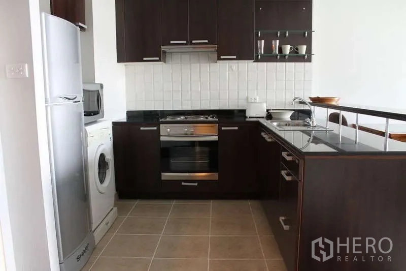 คอนโด ให้เช่าในSathon, Bangkok - มุมมองครัวรูปตัวแอล มีตู้เย็น เครื่องซักผ้า เตาอบ และท็อปหินสีดำ