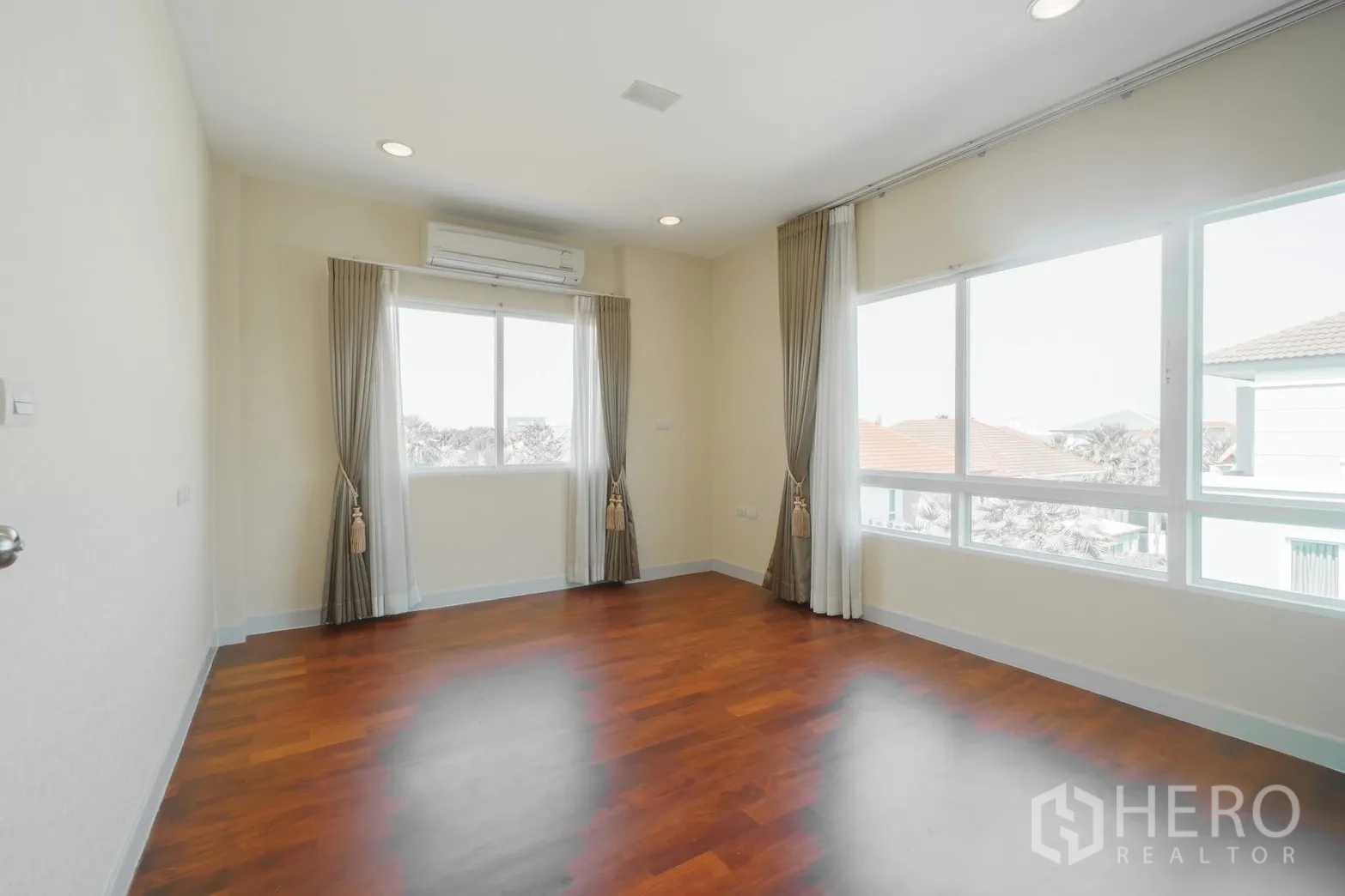 Detached House for rent or sale in Saphan Sung, Bangkok - Bright bedroom with large windows, curtains and wood flooring.