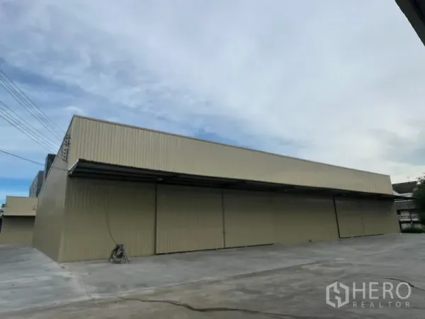 Warehouse for rent in Phra Khanong, Bangkok - Angle view of a modern single-storey warehouse with a deep awning and spacious truck-friendly driveway.